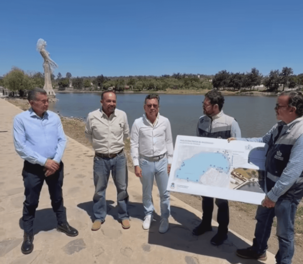 Pablo Lemus Navarro presenta el proyecto del Malecón en la presa El Ocotillo, acompañado de funcionarios y un plano del desarrollo.