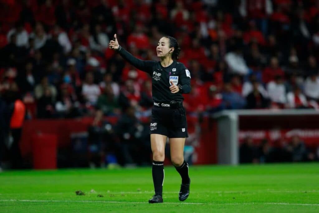 Katia Itzel García, árbitra mexicana, dirigiendo un partido de futbol, levantando el pulgar en señal de aprobación.