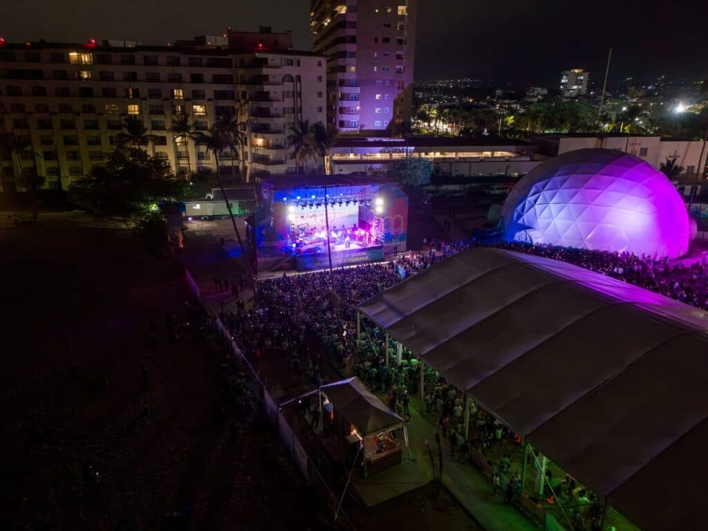 Gran multitud disfruta de un concierto al aire libre en Jalisco, con luces coloridas y un escenario iluminado durante el Mundial.