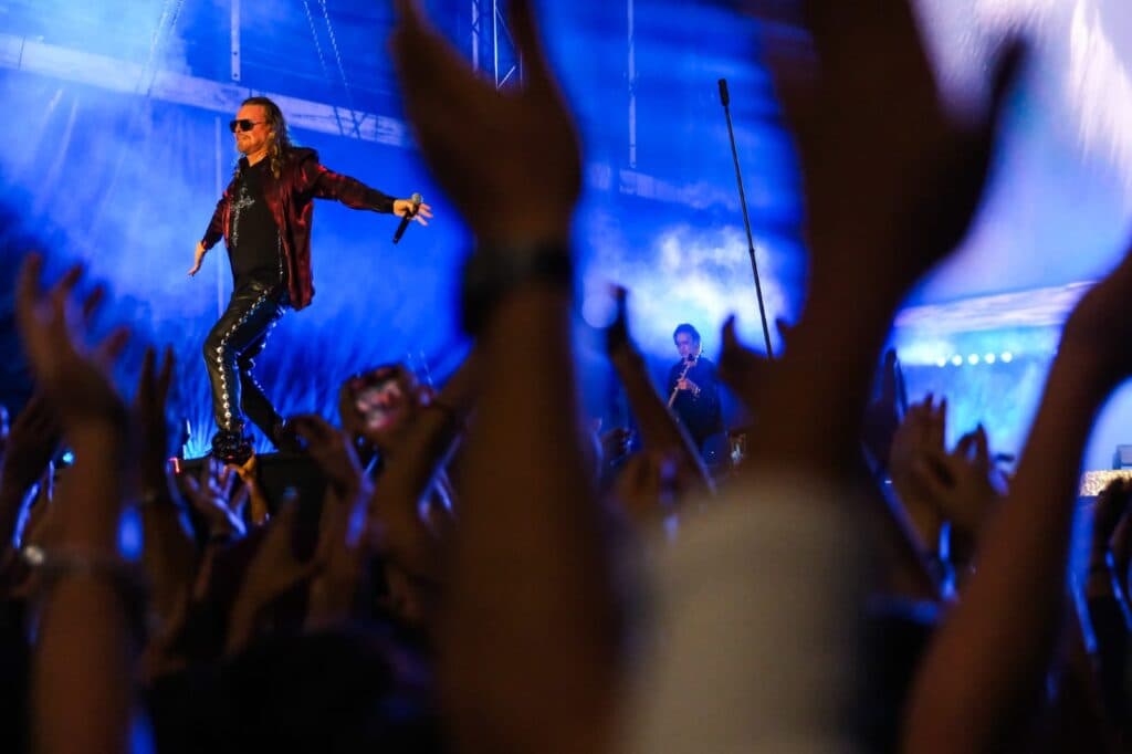 Vocalista de Maná enérgico sobre el escenario mientras el público levanta las manos en La Minerva durante el concierto