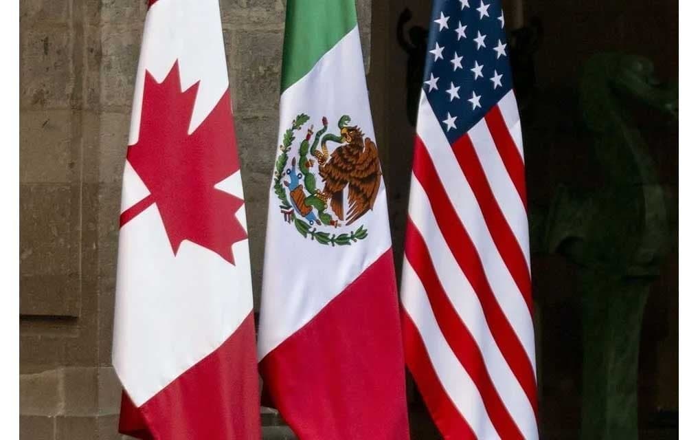 Banderas de México, Estados Unidos y Canadá en un evento relacionado con el T-MEC, simbolizando la negociación comercial entre los países.