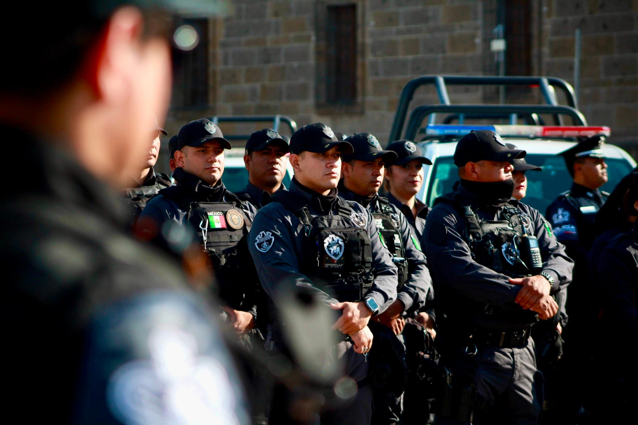Agentes de policía en uniforme negro, en formación, durante un evento de seguridad pública en una ciudad mexicana.