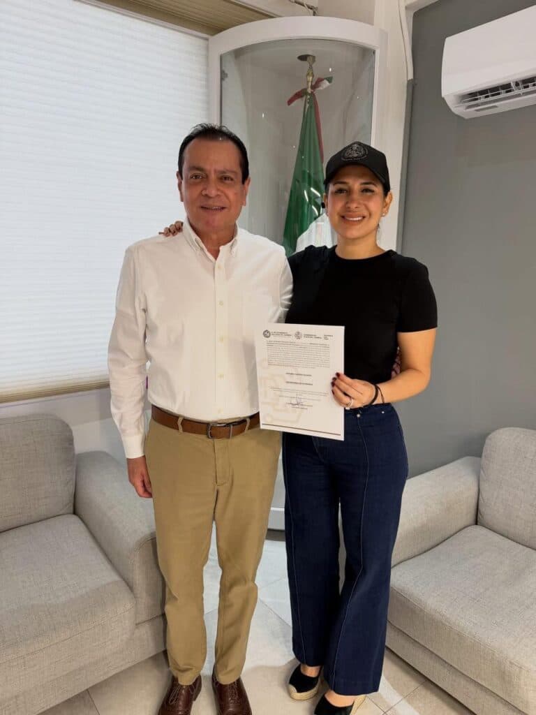 Estefanía Mercado y Arturo Castro posan juntos sosteniendo un documento oficial en la nueva Secretaría de Gobierno de Playa del Carmen.