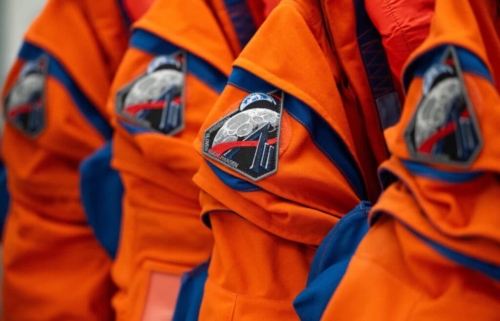 Uniformes de astronautas de la misión Artemis III, con parches que representan la exploración lunar y la tecnología espacial.