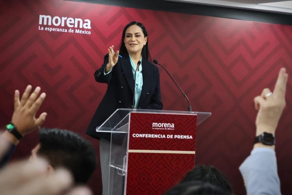 Ariadna Montiel Reyes, presidenta de Morena, habla en conferencia de prensa mientras miembros del público levantan la mano.