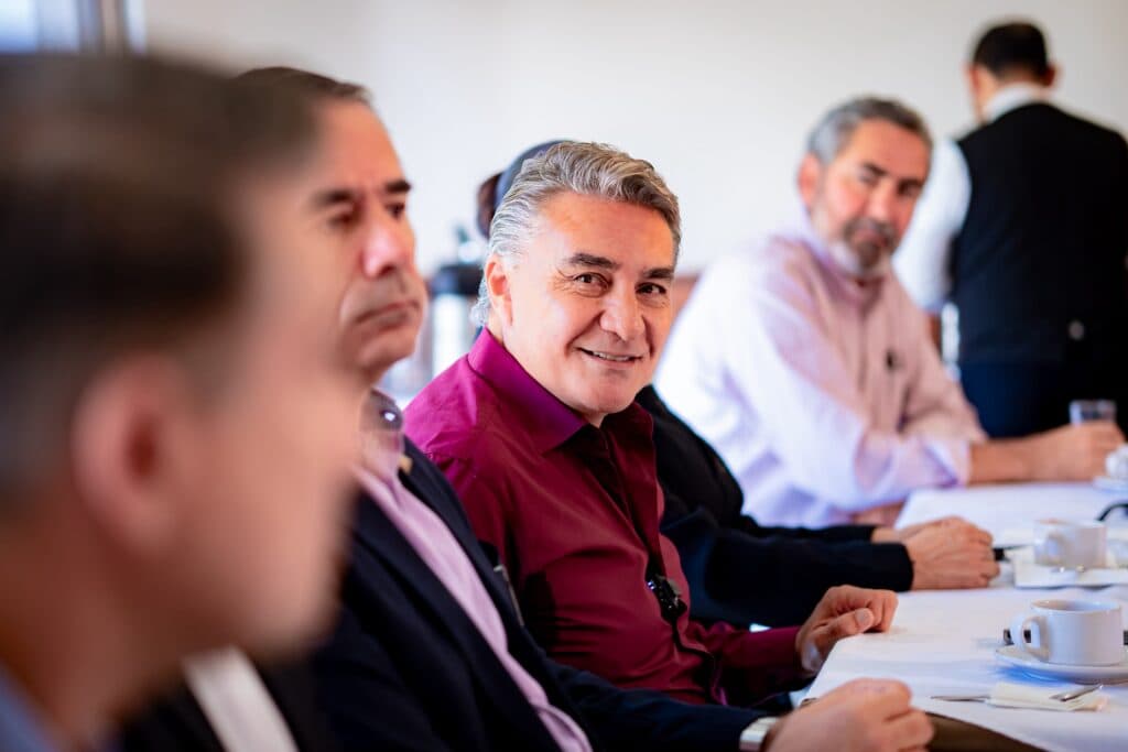 Jesús Ruiz Uribe sonríe mientras participa en una reunión con miembros del Grupo Unidos por Tijuana, abordando temas de desarrollo y seguridad.