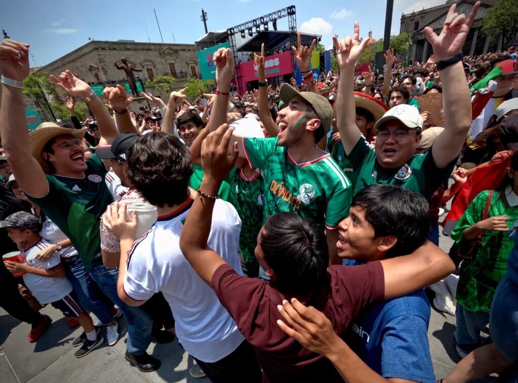 Aficionados celebrando con entusiasmo en el FIFA Fan Festival™ Guadalajara tras el triunfo de México sobre Sudáfrica, con ambiente festivo.