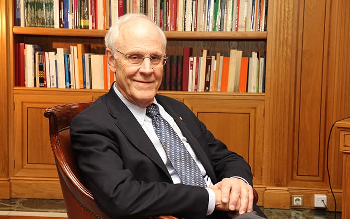 David Gross, físico y Premio Nobel, sentado en un sillón frente a una estantería llena de libros, durante una entrevista