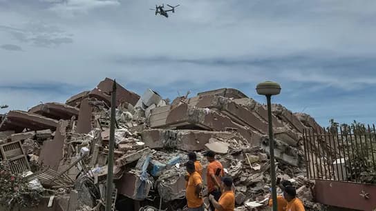 Rescatistas en la zona de escombros tras el terremoto en Venezuela, observan un dron que realiza operaciones de búsqueda.
