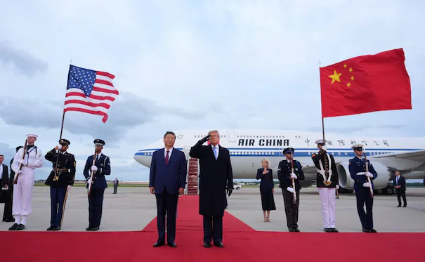 Xi Jinping y Donald Trump en la base aérea Andrews, saludando con banderas de Estados Unidos y China en la recepción oficial.