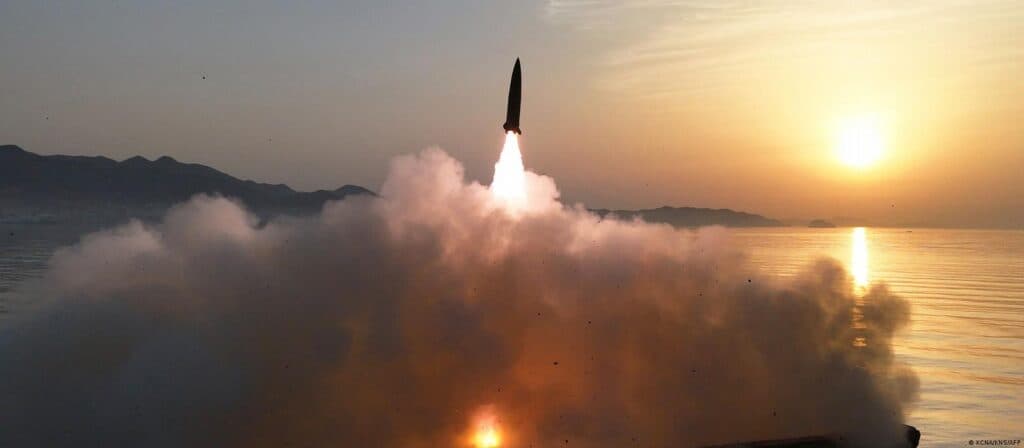 Lanzamiento de un misil balístico al amanecer desde la costa de Corea del Norte, generando una gran nube de humo.
