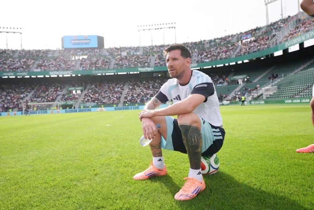 Lionel Messi sentado en el césped del estadio, reflexionando antes de un partido con la selección argentina.