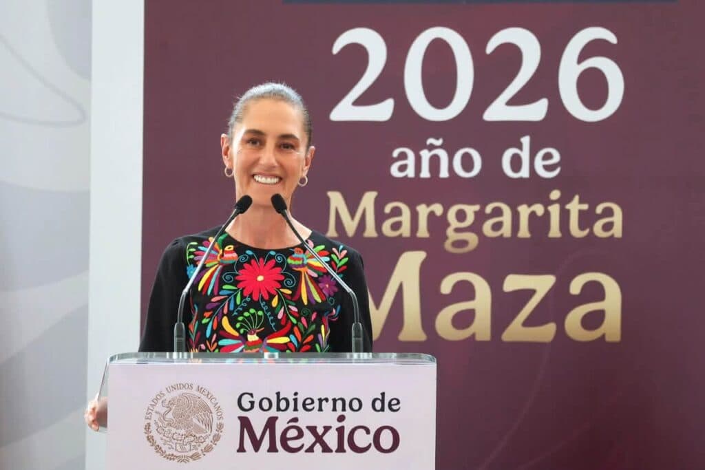 Claudia Sheinbaum sonríe mientras se dirige al público desde un podio con el logo del Gobierno de México, en un evento sobre Margarita Maza.