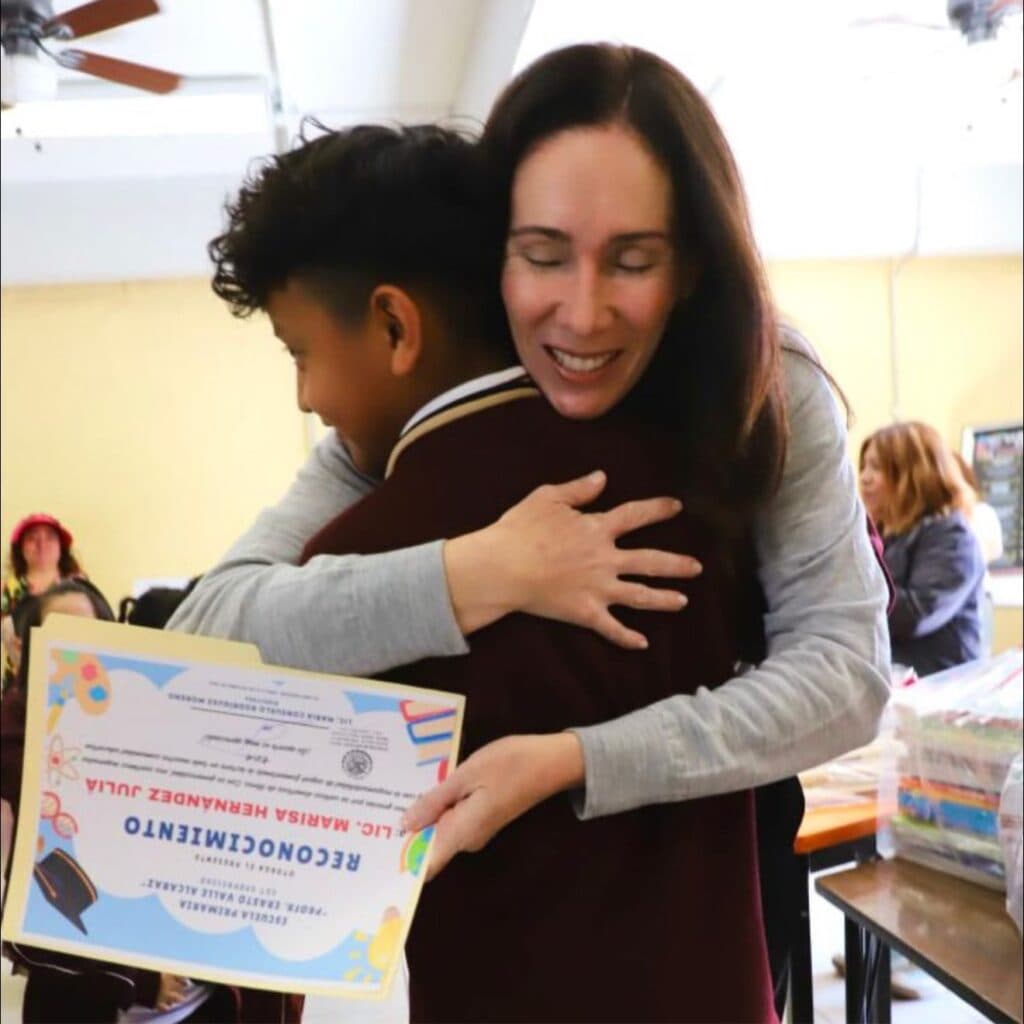 Marisa Hernández Juliá abraza a un niño mientras le entrega un reconocimiento en un evento del Voluntariado de Álvaro Obregón.