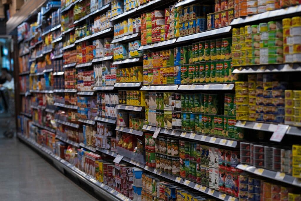 Estantes de supermercado repletos de productos enlatados y envasados, reflejando el impacto de posibles aumentos de impuestos en alimentos.