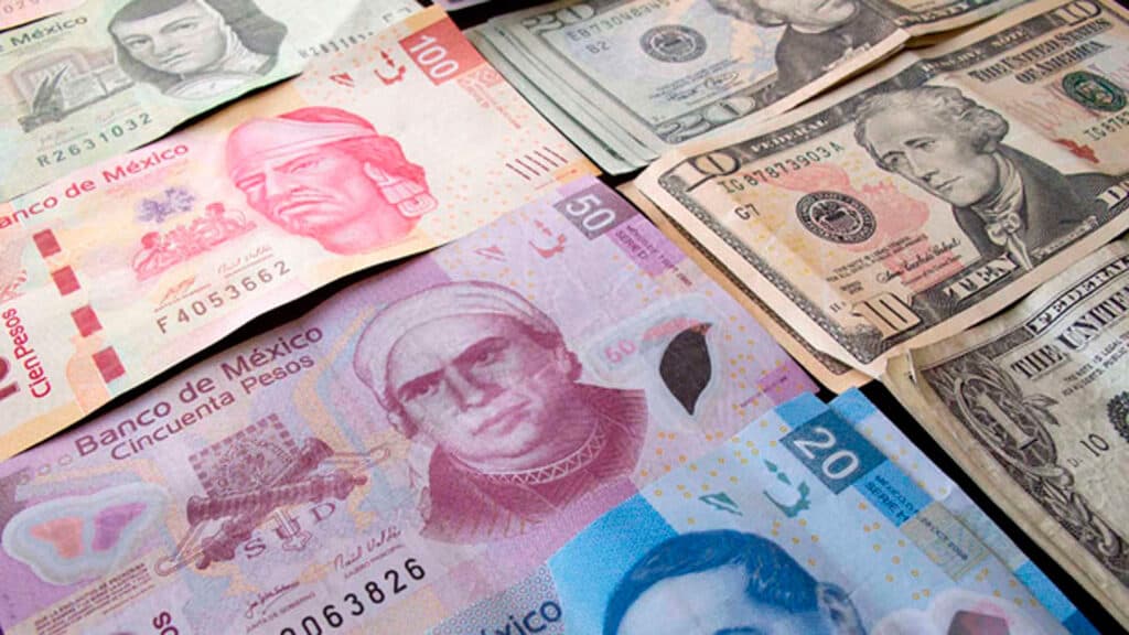 Billetes de pesos mexicanos y dólares estadounidenses sobre una superficie, ilustrando el tipo de cambio entre ambas monedas.