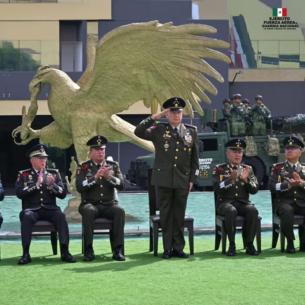 Ceremonia del 205 aniversario de la Sedena, con el general Trevilla en el centro, saludando frente a un águila monumental y oficiales.