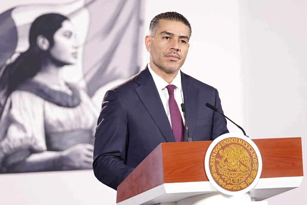 Omar García Harfuch, secretario de Seguridad, habla sobre la disminución de la percepción de inseguridad en México, con fondo de mural.