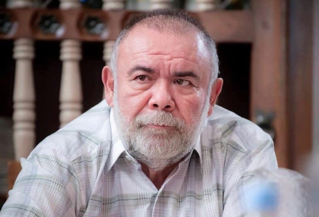 Jesús Ochoa con expresión seria, sentado en una mesa, en un entorno que sugiere un hogar, generando preocupación por su salud tras un accidente.